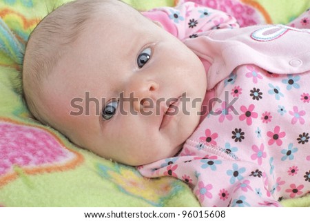 Closeup head and shoulders portrait of a new baby with clothing and blanket in pastel spring colors. Horizontal layout.