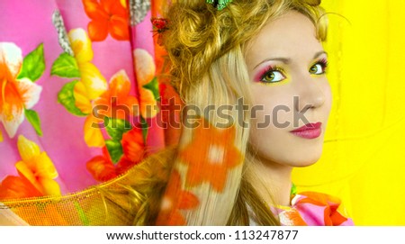 Young girl with pink and yellow makeup and hair colouring in the shape of flowers.