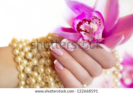 French Manicure To A Woman\'S Hand With An Orchid And Beads.