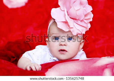 Little beautiful girl with blue eyes and a flower rose on his head.