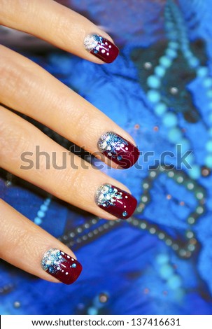 Holiday Nails With A Manicure With Claret Varnish And Sparkles On The Decorative Background.