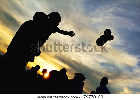 On the feast of the child at the hands of men reaching for balloons evening at sunset.