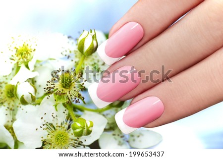 French manicure with pink and white lacquer against the background of flowers