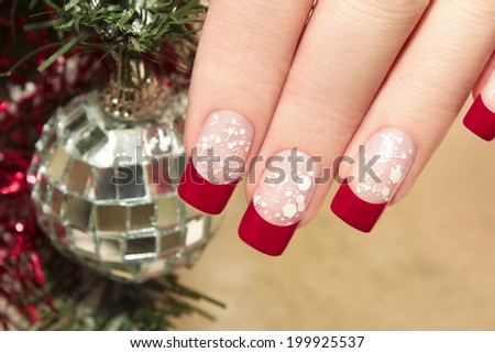 Red nail Polish on artificial nails with white crumb and new year\'s accessories.