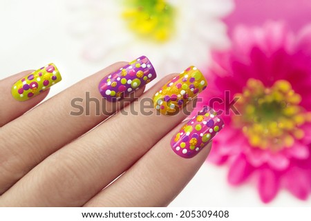 Colorful manicure with points on a lilac,yellow,pink,g reen background nails.