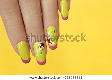 French green manicure with design of flowers with rhinestones on a yellow background.