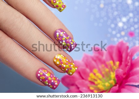 Manicure with multi-colored varnish for the nails and the same design in the form of points on women s hand