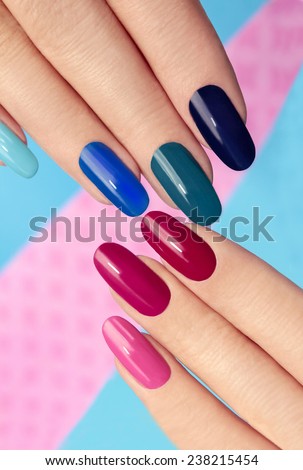 Blue pink nail Polish on long nails on a colored background.