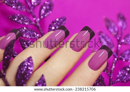 Lilac manicure on female hand with purple sparkles.