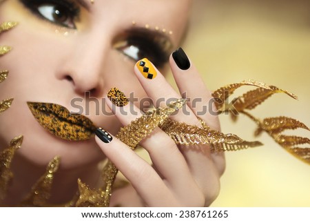Caviar manicure in yellow black nails with black and gold rhinestones on a brilliant background.