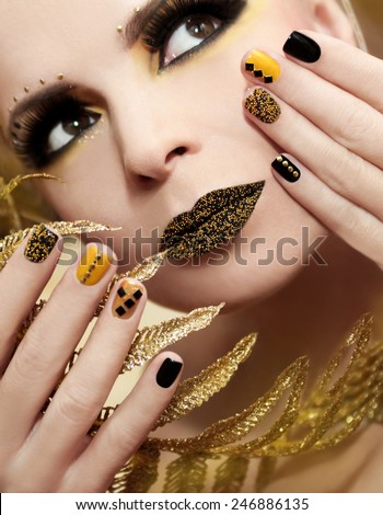 Caviar manicure in yellow and black nail Polish on the girl with false eyelashes and rhinestones of different shapes.