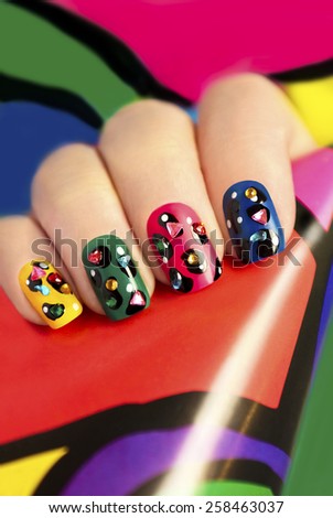 Colored nail Polish on a woman\'s nails with rhinestones and design points.