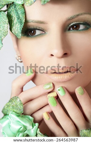 Green makeup and nail Polish with sparkles and rhinestones of different shapes.