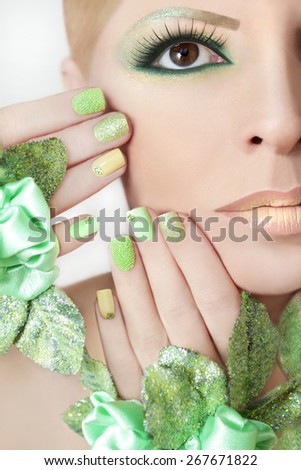 Green makeup and nail Polish with sparkles and rhinestones of different shapes.