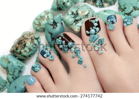 Pedicure with turquoise stones and jewelry made of turquoise on the women\'s foot.