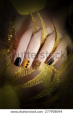 Black and yellow manicure with different colors of nail Polish and rhinestones of different shapes.
