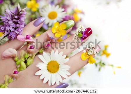Nail design with flowers and colored lacquer on a woman\'s hand.