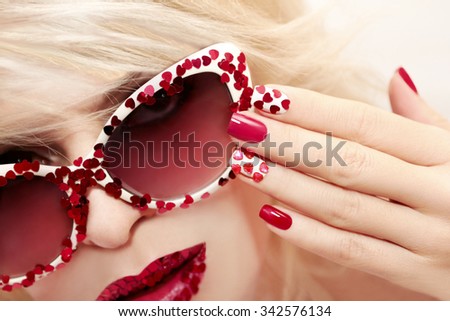 Multicolored manicure with red and white nail Polish decorated with rhinestones in the shape of hearts.