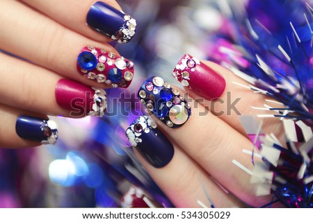 Christmas winter blue manicure with rhinestones of different shapes and sequins in the form of snow on female hand with tinsel.