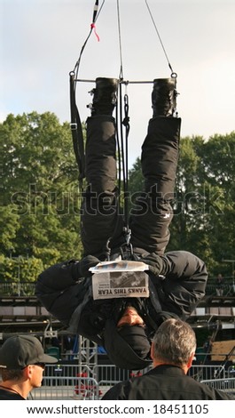 NEW YORK, NY -- SEPTEMBER 24, 2008: David Blaine reads the newspaper while hanging upside down in Central Park on the final morning of his \