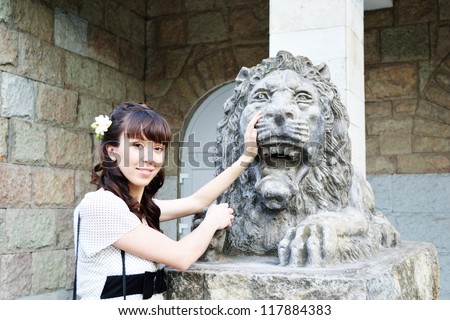 Portrait of young beautiful girl with lion statue