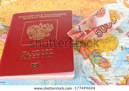 Russian international passport with origami plane made from money on the world map