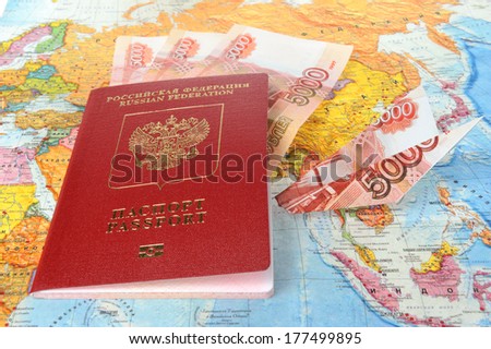 Russian international passport with money within and origami plane made from money on the world map