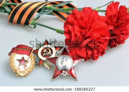 Red carnations tied with Saint George ribbon and orders of Great patriotic war on gray background