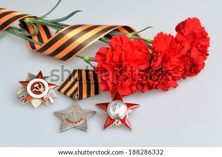 Red carnations tied with Saint George ribbon and orders of Great patriotic war on gray background