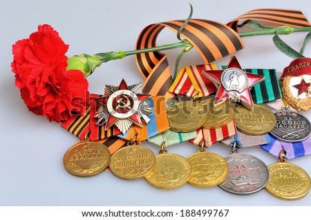 Red flower with Saint George ribbon and military awards of the Great Patriotic war on gray