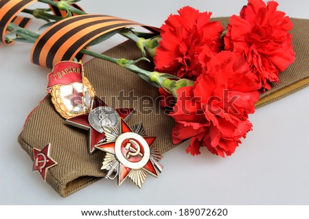 Military cap with red flowers, Saint George ribbon and orders of Great Patriotic war on gray