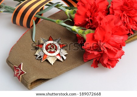 Military cap with order of Great Patriotic war and red flowers tied by Saint George ribbon