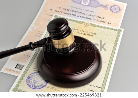 Hammer of judge with maternal and birth certificates on gray background