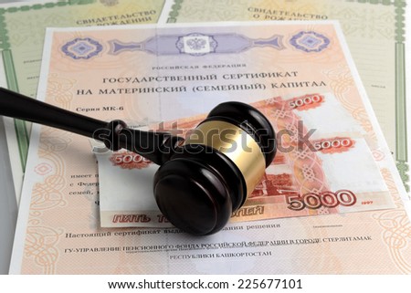 Hammer of judge with money, maternal and birth certificates on gray