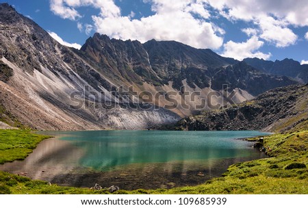 Mountain Lake in the alpine tundra of mountain peaks. Emerald color of pure water comes from a very large depth