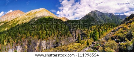 View from a mountain trail leading to the mountain pass in the Eastern Sayan. At the bottom and the center - a small mountain river canyon. Republic of Buryatia. panorama