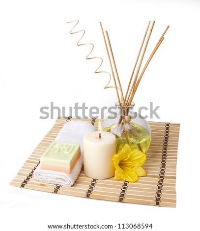 spa setting with aroma sticks, candle, soap, towel and flower on bamboo mat isolated on white