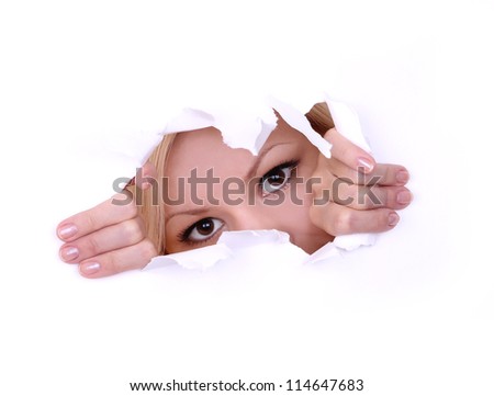 blonde young woman peeping through hole on paper