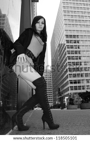 fashion girl in sexy boots posing in big city, urban outfit, black and white