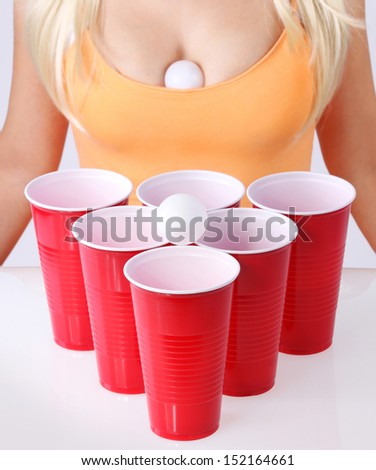 Beer pong. Red plastic cups with ping pong balls and blonde girl in sexy tank top. Closeup