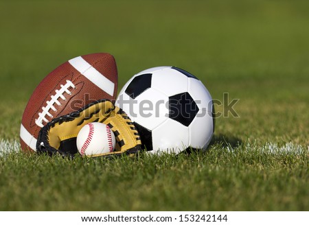 Sports Balls On The Field With Yard Line. Soccer Ball, American Football And Baseball In Yellow Glove On Green Grass. Outdoors