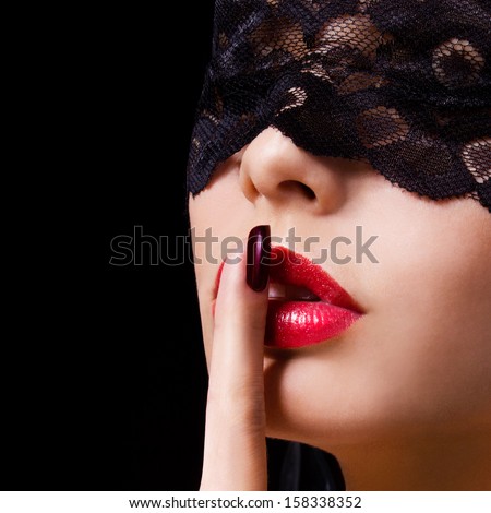 Hush. Sexy Woman With Finger On Her Red Lips Showing Shush. Erotic Girl With Lace Mask Over Black Background.