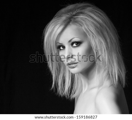 Fashion portrait. Beautiful blonde woman with professional makeup and hairstyle, over black background. Vogue style model. Black and White