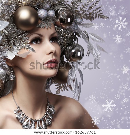 Christmas Woman With New Year Decorated Hairstyle. Snow Queen. Portrait Of Fashion Girl With Silver And Gold Christmas Balls Over Snowflakes Background. Holiday Card