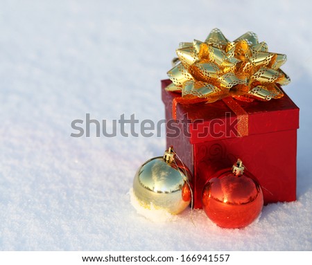 Christmas Gift Box with Shiny Balls on Snow. Outside. Winter Sunny Day.