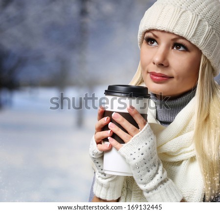 Girl with Takeaway Coffee Cup over Winter background. Blonde Beautiful Young Woman in Knitted Hat and Scarf. Portrait