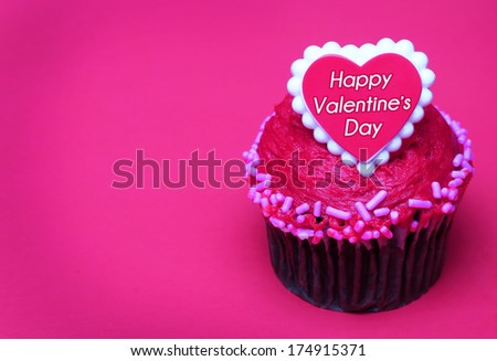 Chocolate cupcake with Valentines heart on the top, over hot pink background with space for the text.