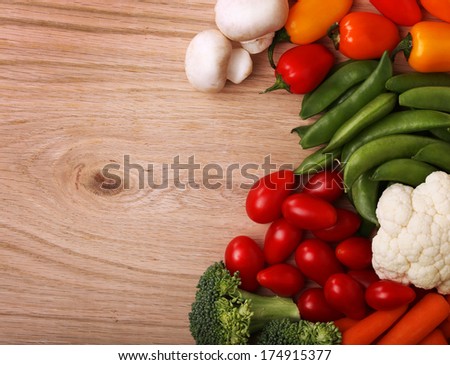 Healthy Organic Vegetables on a Wooden Background. Peppers, Mushrooms, Peas, Cauliflower, Tomatoes, Carrots and Broccoli.