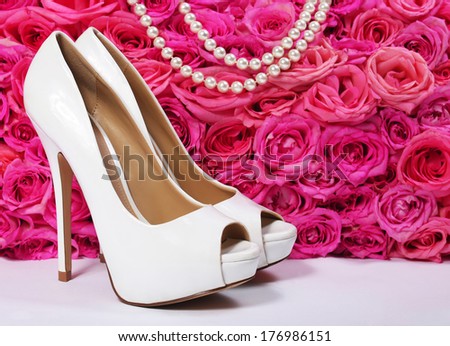 Bridal Shoes and Roses. White Heels over Hot Pink Flowers with Pearl Necklace.  Wedding