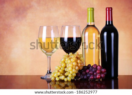 Bottles of Red and White Wine with Fresh Grapes. Glasses of Wine over Beige Background